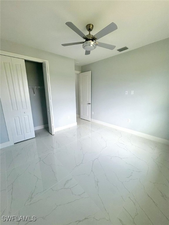 unfurnished bedroom with ceiling fan and a closet