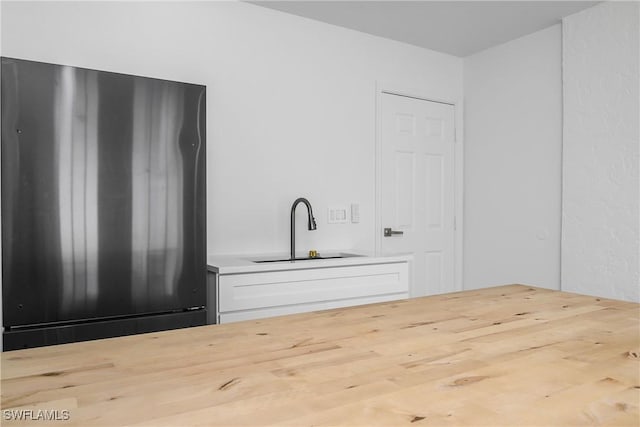 bar with stainless steel fridge, sink, and white cabinets