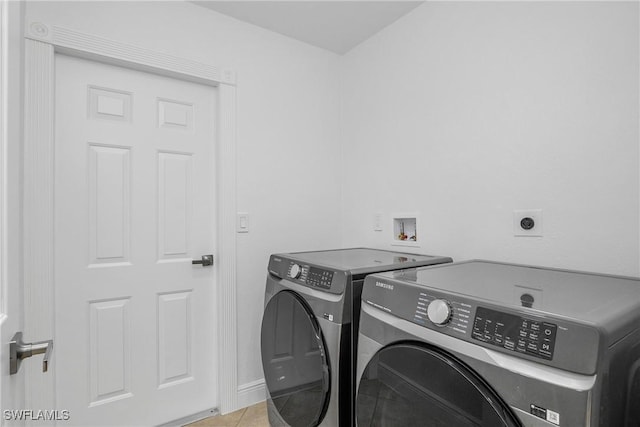 laundry area with washing machine and dryer and light tile patterned floors