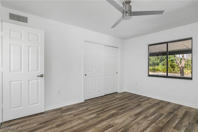 unfurnished bedroom with ceiling fan, a closet, and dark wood-type flooring