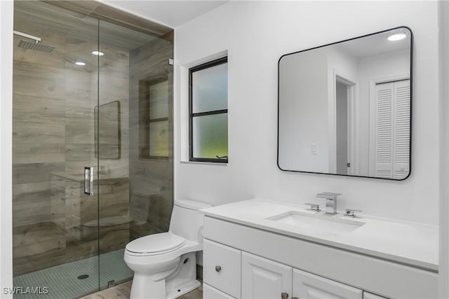 bathroom featuring vanity, a shower with shower door, and toilet