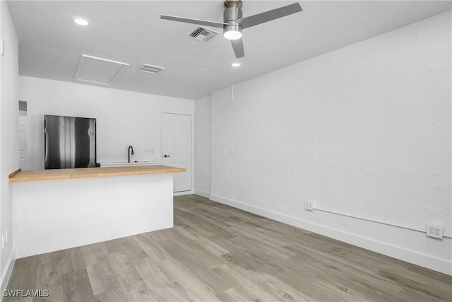 unfurnished living room featuring ceiling fan and light hardwood / wood-style flooring