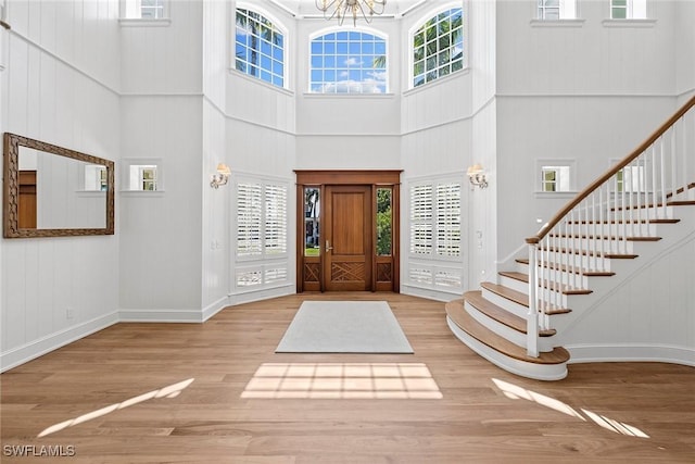 entryway featuring a chandelier, wood-type flooring, and a towering ceiling