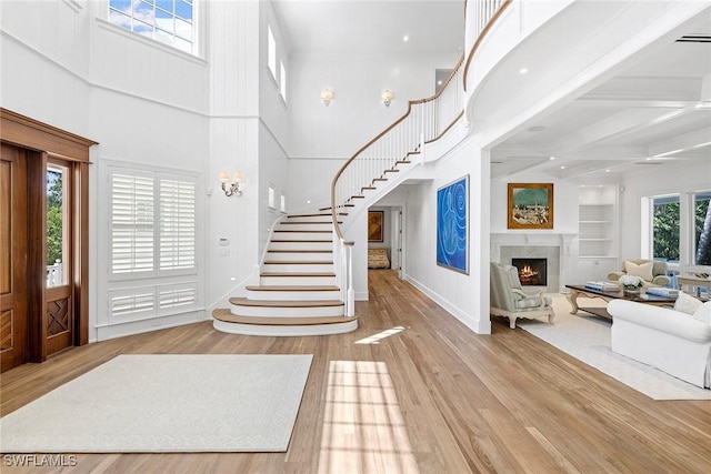 entrance foyer with beamed ceiling, light wood-type flooring, and a high ceiling