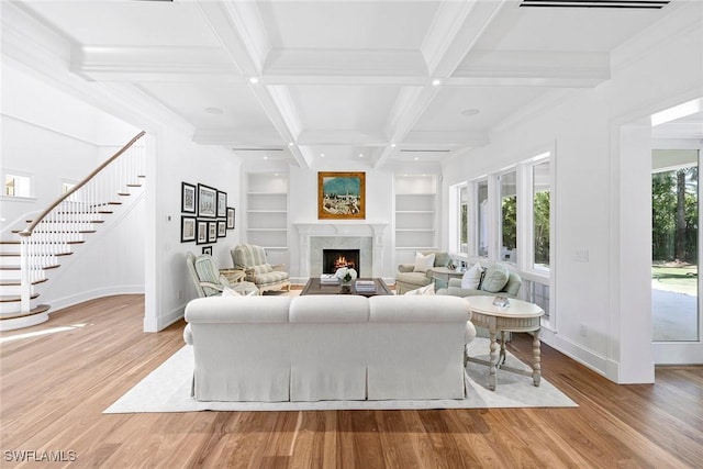 living room featuring a high end fireplace, beamed ceiling, light hardwood / wood-style floors, and coffered ceiling