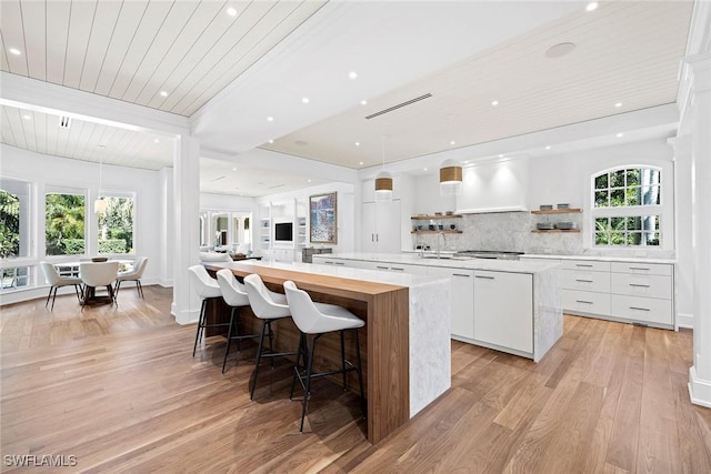 kitchen with a healthy amount of sunlight, light hardwood / wood-style floors, white cabinetry, and a spacious island