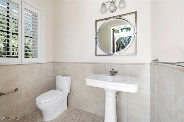 bathroom featuring toilet and tile walls