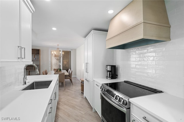 kitchen featuring custom exhaust hood, stainless steel electric stove, sink, light hardwood / wood-style flooring, and white cabinets