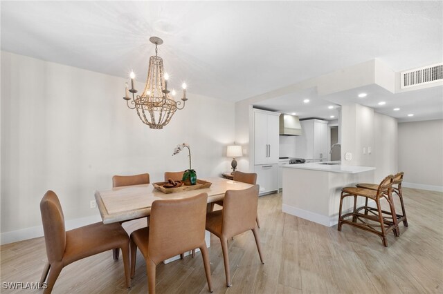 dining room featuring sink, light hardwood / wood-style flooring, and an inviting chandelier