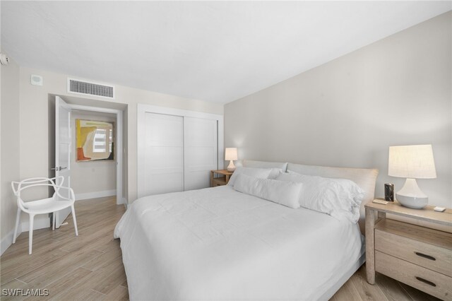 bedroom with light hardwood / wood-style floors and a closet