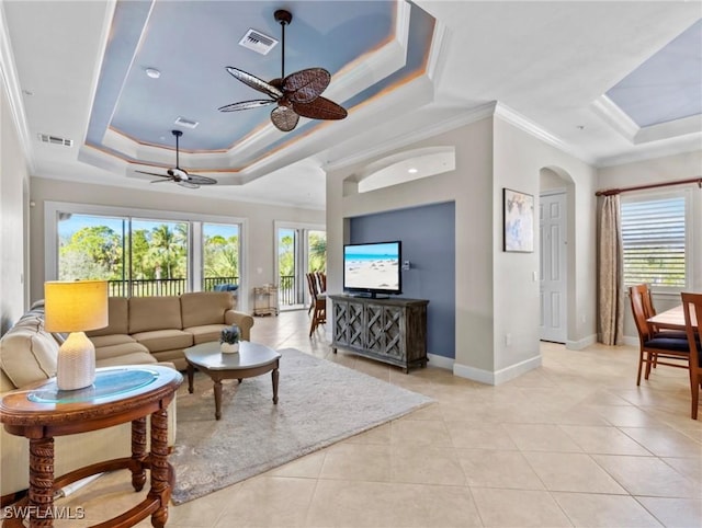 tiled living room featuring ceiling fan, a raised ceiling, and ornamental molding