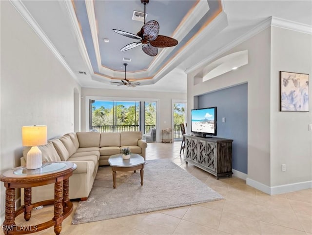 living room with a tray ceiling, ceiling fan, light tile patterned flooring, and ornamental molding