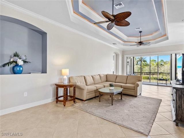 living room featuring light tile patterned flooring, crown molding, and a tray ceiling