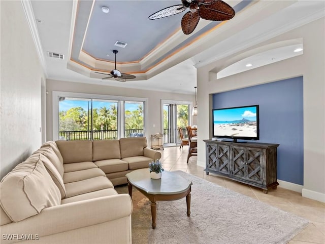 tiled living room with ceiling fan, a raised ceiling, and crown molding