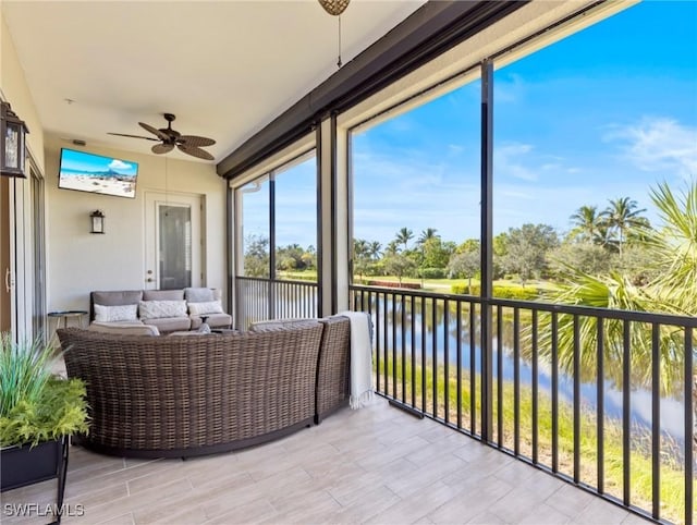 sunroom featuring a water view and ceiling fan