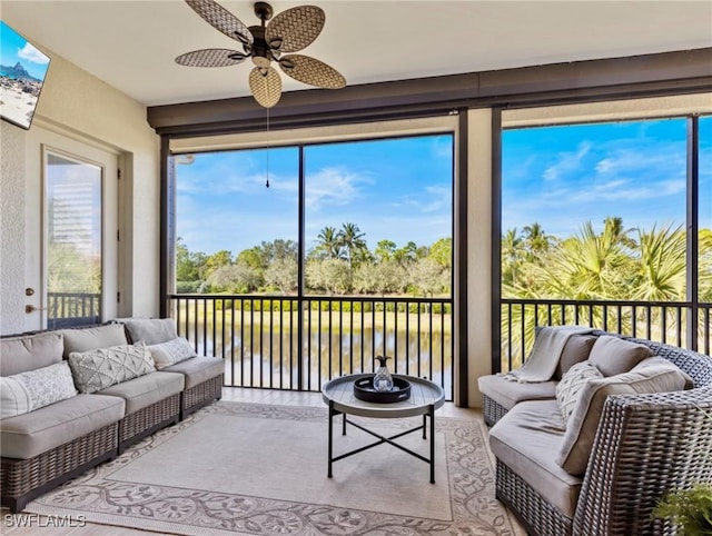 sunroom featuring a water view and ceiling fan