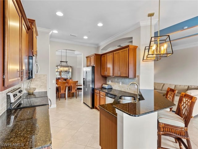 kitchen featuring sink, dark stone counters, decorative light fixtures, and appliances with stainless steel finishes