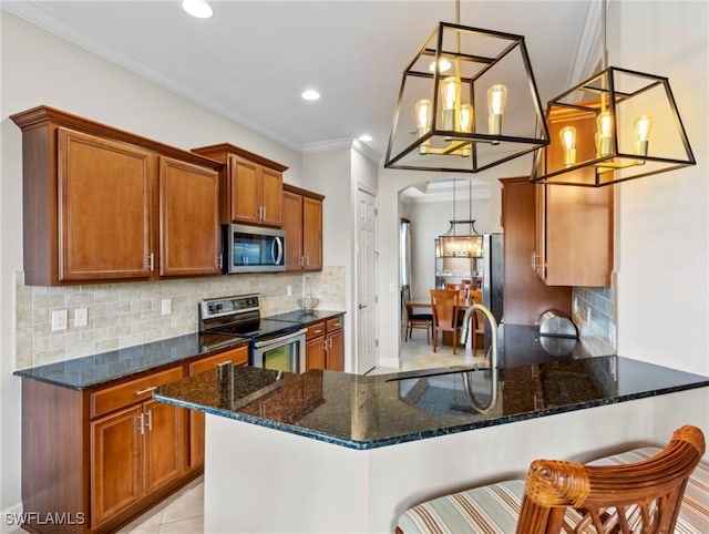 kitchen with a breakfast bar, stainless steel appliances, hanging light fixtures, and dark stone countertops