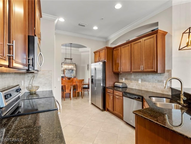 kitchen featuring crown molding, sink, dark stone countertops, appliances with stainless steel finishes, and decorative light fixtures