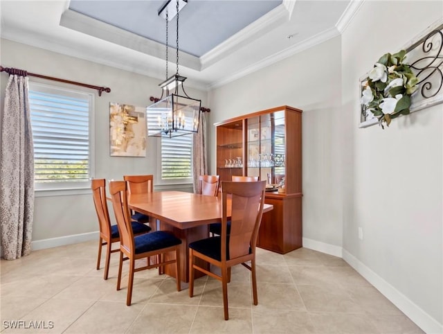 tiled dining space featuring a raised ceiling, crown molding, and a chandelier