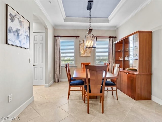 tiled dining room with a raised ceiling, ornamental molding, and a notable chandelier