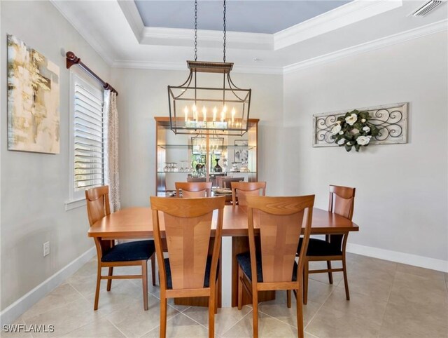 tiled dining area with a tray ceiling, crown molding, and a notable chandelier