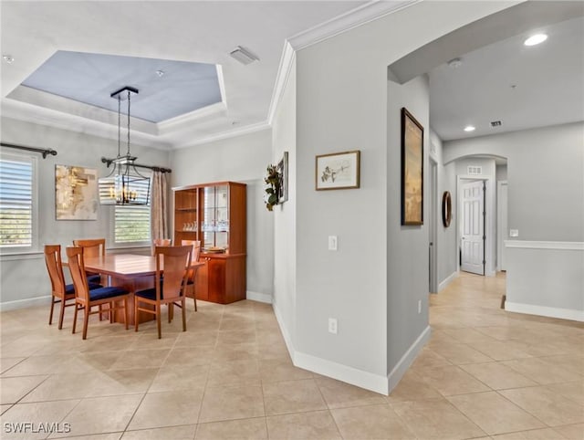 dining area with a notable chandelier, a raised ceiling, light tile patterned floors, and crown molding