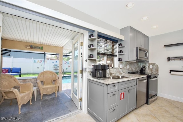 kitchen featuring gray cabinets, sink, backsplash, and appliances with stainless steel finishes