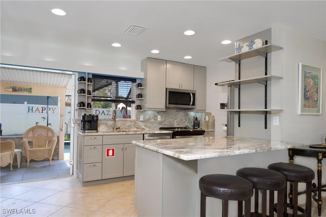 kitchen featuring visible vents, appliances with stainless steel finishes, light stone countertops, gray cabinetry, and open shelves