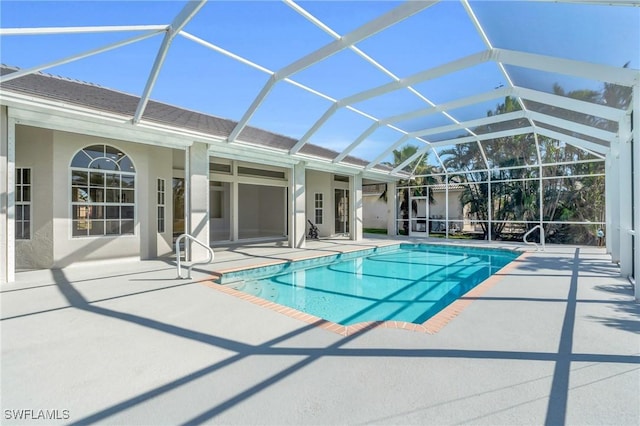 view of swimming pool featuring glass enclosure and a patio area