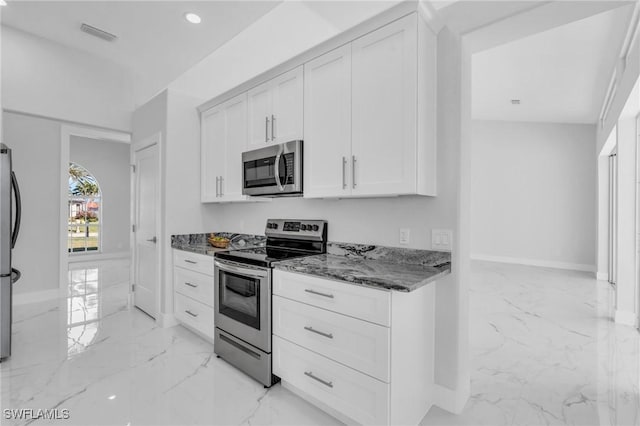 kitchen featuring appliances with stainless steel finishes, white cabinetry, and dark stone counters