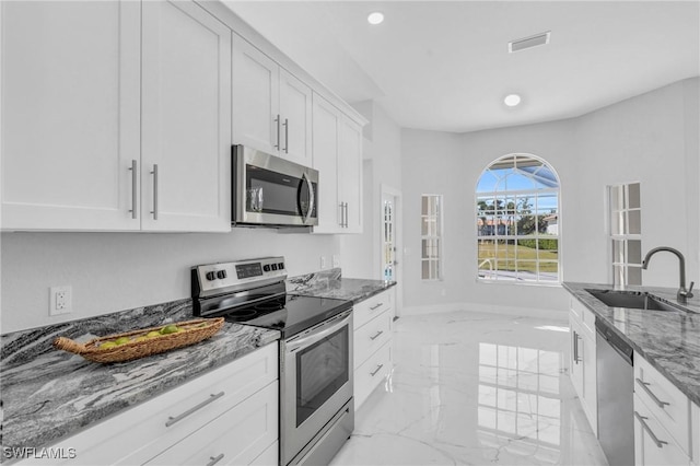 kitchen featuring white cabinets, stone counters, sink, and appliances with stainless steel finishes