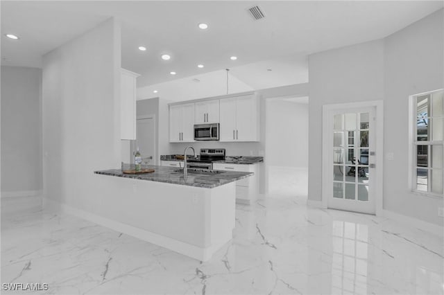 kitchen featuring white cabinetry, sink, stainless steel appliances, kitchen peninsula, and dark stone countertops