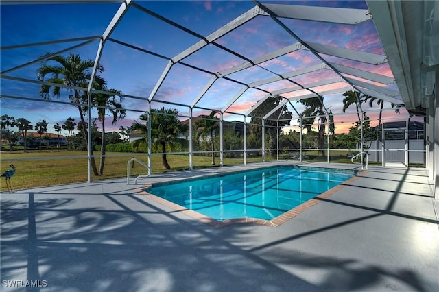 pool at dusk with glass enclosure, a yard, and a patio