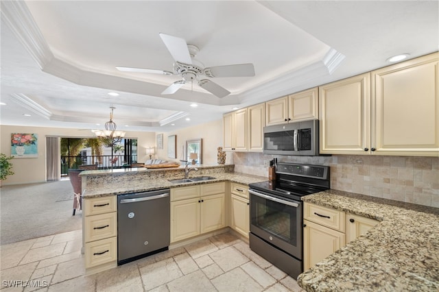 kitchen featuring kitchen peninsula, appliances with stainless steel finishes, a raised ceiling, sink, and cream cabinets