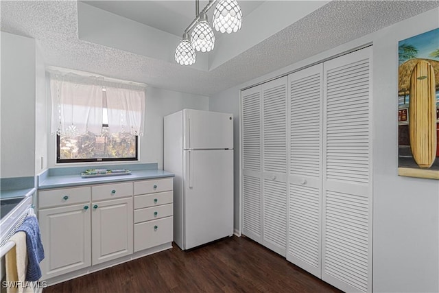 kitchen featuring hanging light fixtures, dark hardwood / wood-style floors, white fridge, a textured ceiling, and white cabinets