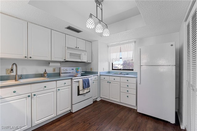 kitchen featuring sink, hanging light fixtures, dark hardwood / wood-style flooring, white appliances, and white cabinets