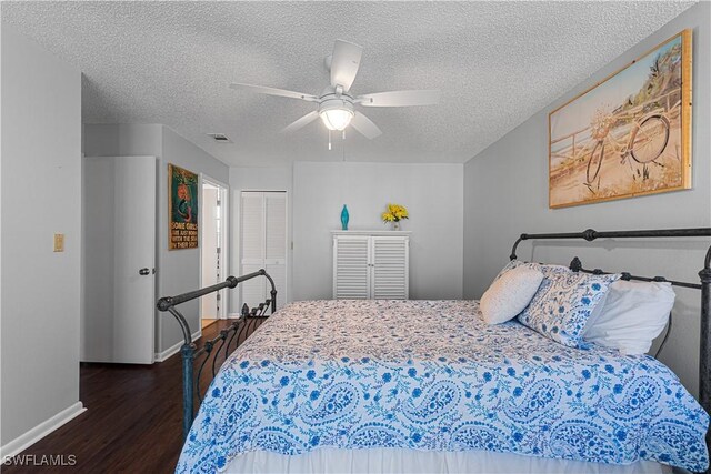 bedroom with a textured ceiling, a closet, ceiling fan, and dark wood-type flooring