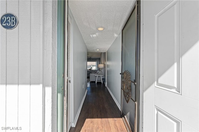 corridor featuring a textured ceiling and dark wood-type flooring