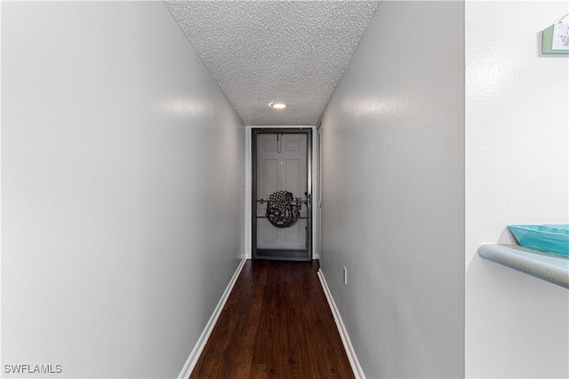 hall with a textured ceiling and dark wood-type flooring