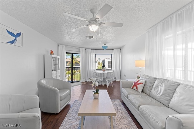 living room with ceiling fan, dark wood-type flooring, and a textured ceiling