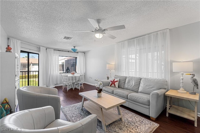 living room featuring a textured ceiling, ceiling fan, and dark wood-type flooring