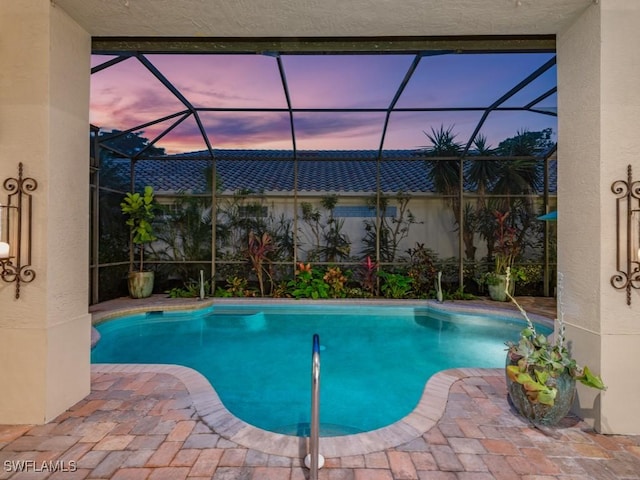 pool at dusk with a lanai and a patio