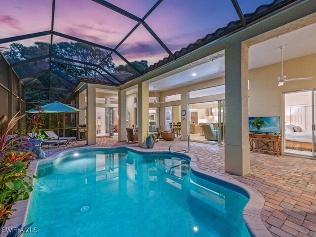 view of swimming pool with pool water feature, a lanai, a patio area, and ceiling fan