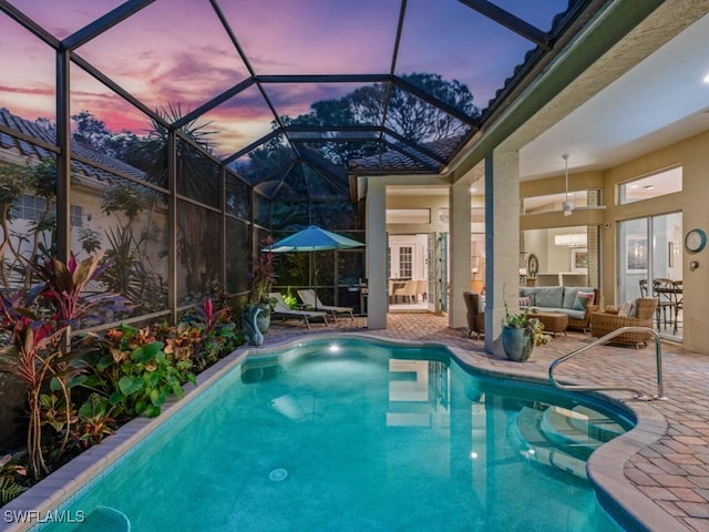 pool at dusk with an outdoor living space, a lanai, and a patio area