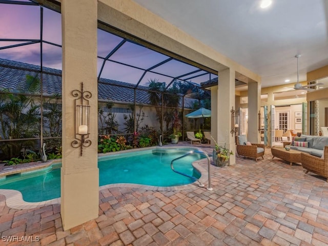 pool at dusk featuring a patio, outdoor lounge area, and a lanai