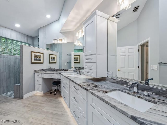 bathroom featuring a tile shower, vanity, and vaulted ceiling