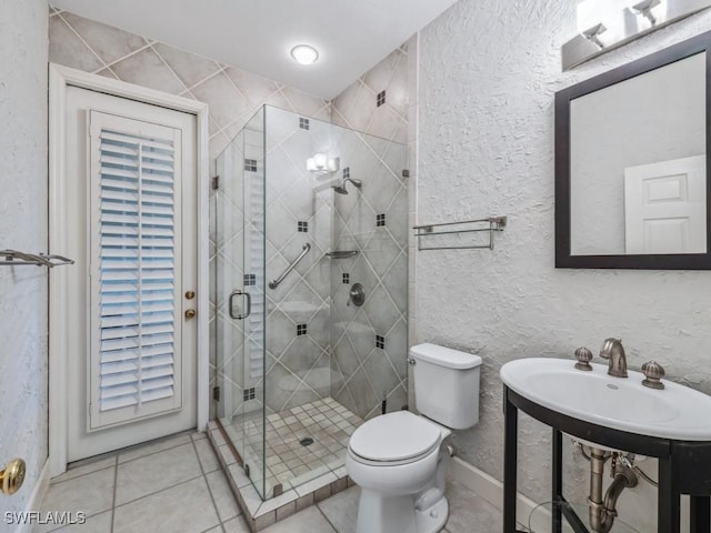 bathroom with a shower with door, tile patterned floors, and toilet