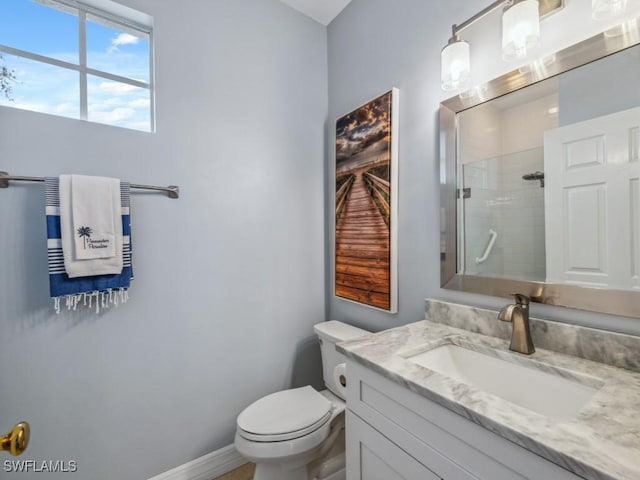 bathroom featuring vanity, a shower with door, and toilet