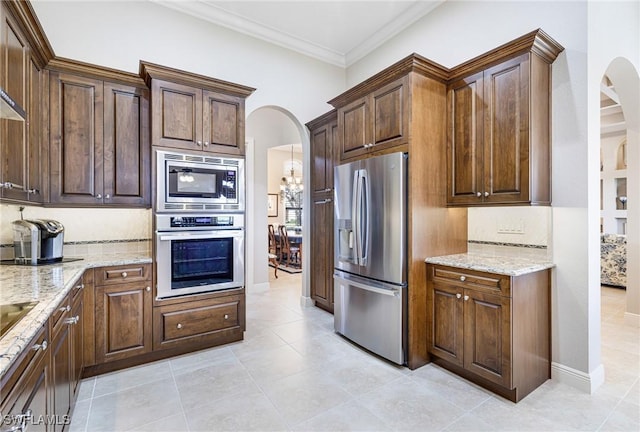 kitchen with light stone countertops, tasteful backsplash, a chandelier, light tile patterned floors, and appliances with stainless steel finishes